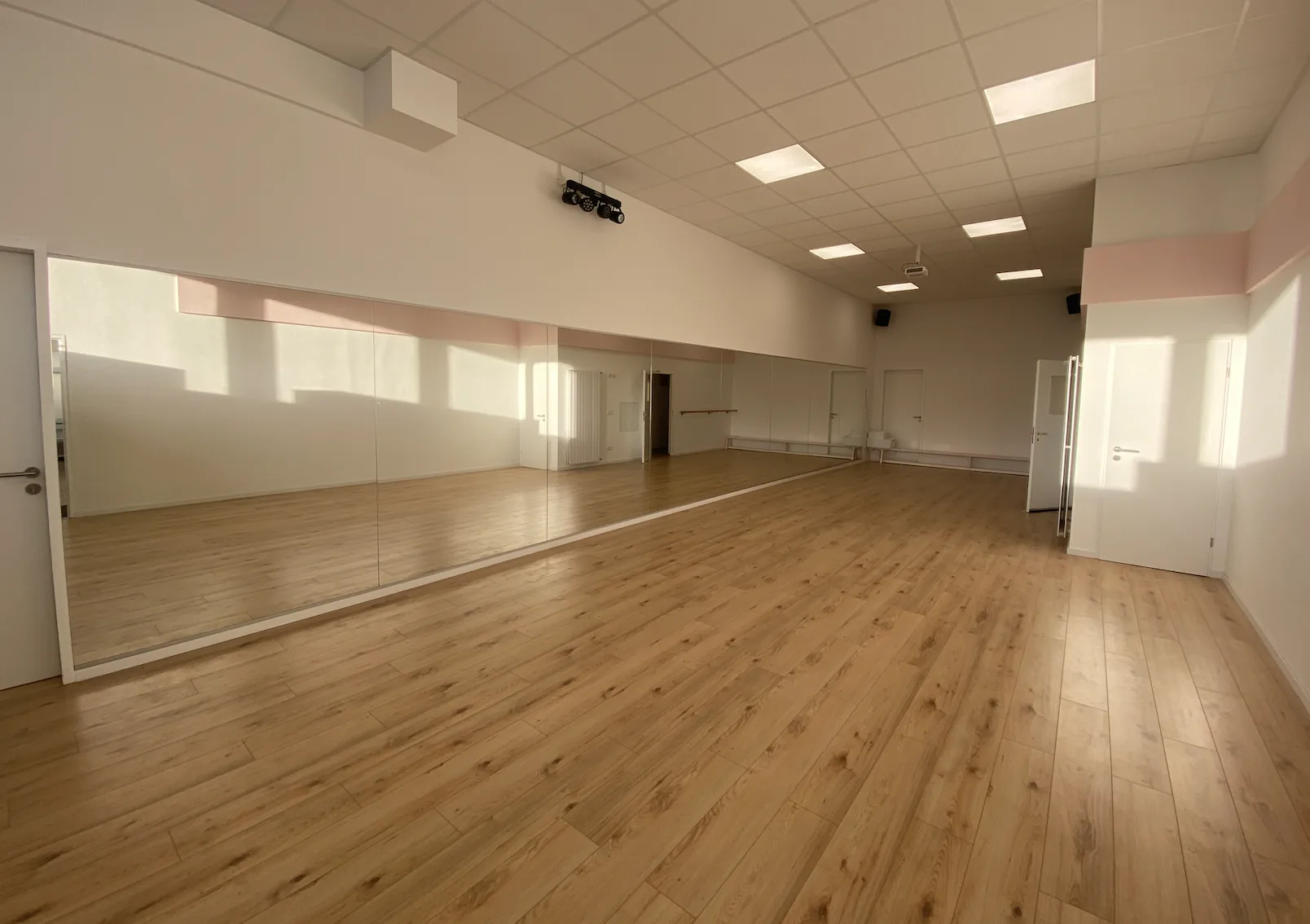 Der helle Kursraum mit Spiegelwand und Holzboden